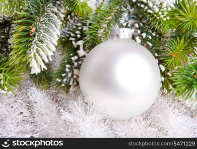 White nacreous glass New Year&rsquo;s ball and snow-covered branches of a Christmas tree