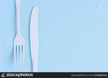 White new clean knife and fork flat lay on blue trendy pastel background with copy space