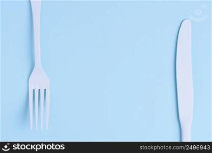 White new clean knife and fork on blue trendy pastel background with copy space