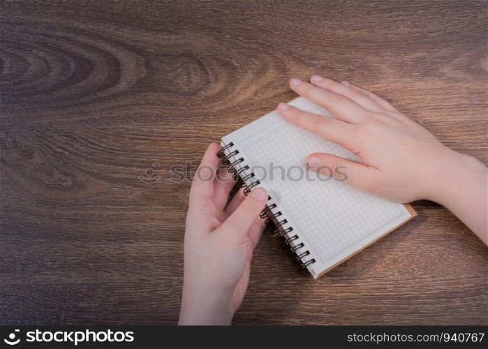 White notebook in hand on a brown color background