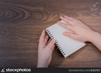 White notebook in hand on a brown color background