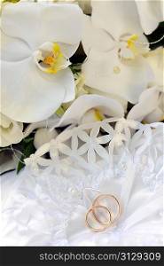 white orchids and wedding rings on bridal pillow