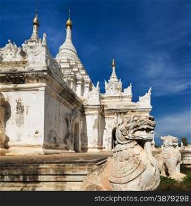 White Pagoda at Inwa ancient city with lions guardian statues. Amazing architecture of old Buddhist Temples. Myanmar (Burma) travel landscapes and destinations