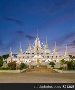 White pagoda or stupa of Asok Maharat buddhist Temple at night, Samut Prakan Province, Thailand. Thai architecture. Tourist attraction landmark.