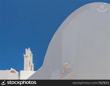 White paint being applied by roller to traditional house in Santorini. Worker repainting traditional cave house on Santorini