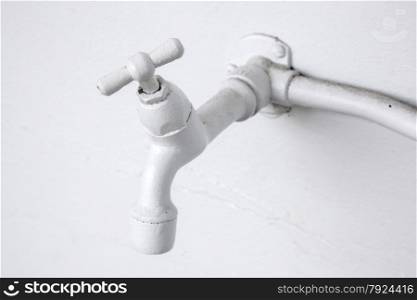 white painted water tap against white washed wall