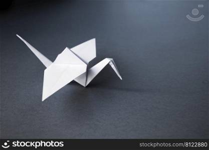 White paper crane origami isolated on a blank grey background.. White paper crane origami isolated on a grey background