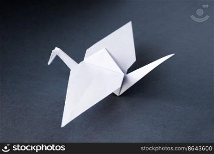 White paper crane origami isolated on a blank grey background.. White paper crane origami isolated on a grey background