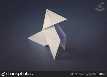 White paper hen origami isolated on a blank grey background. Cocotte en papier. White paper hen origami isolated on a grey background