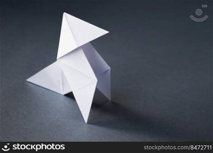 White paper hen origami isolated on a blank grey background. Cocotte en papier. White paper hen origami isolated on a grey background