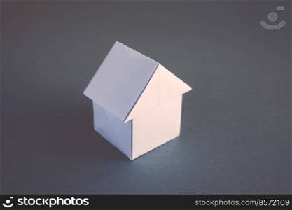White paper house origami isolated on a blank grey background.. White paper house origami isolated on a grey background