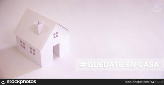 "white paper house with text in spanish "quedate en casa" (stay at home) with copy space. Social distancing campaign during pandemic"