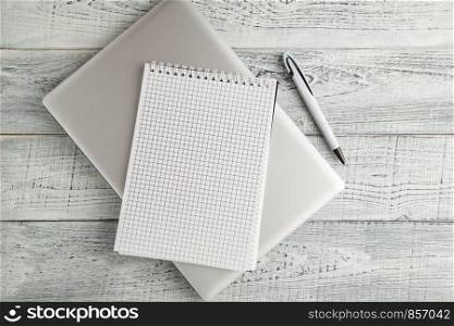 white paper Notepad and laptop on vintage shabby white wooden background. the view from the top. flat lay