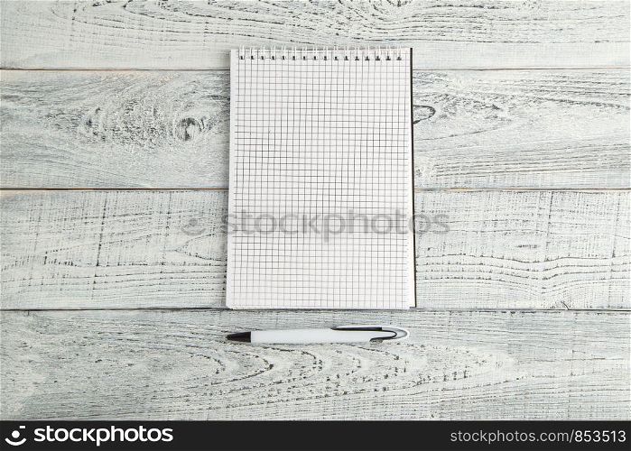 white paper Notepad and white pen on vintage shabby white wooden background