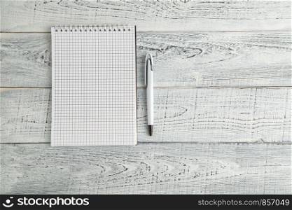 white paper Notepad and white pen on vintage shabby white wooden background