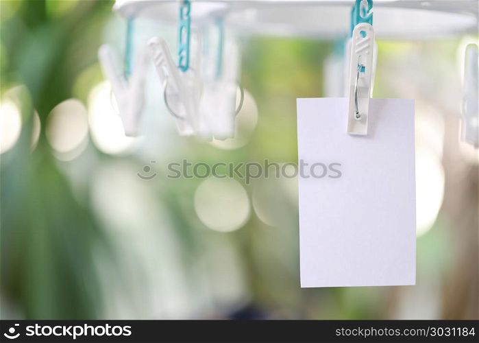 white paper notes hanging in a clothesline.. white paper notes hanging in a clothesline on green bokeh background.