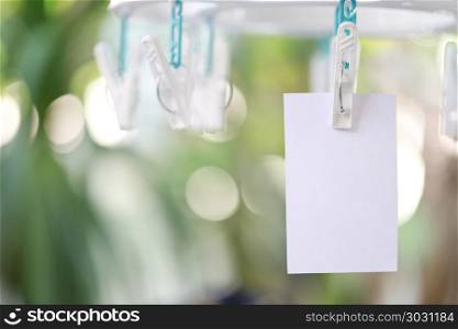 white paper notes hanging in a clothesline.. white paper notes hanging in a clothesline on green bokeh background.