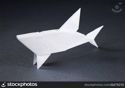 White paper shark origami isolated on a blank grey background. White paper shark origami isolated on a grey background