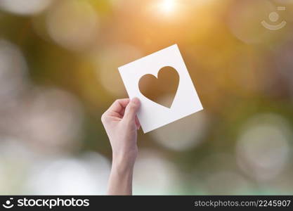 White paper with cut heart shape in a hand