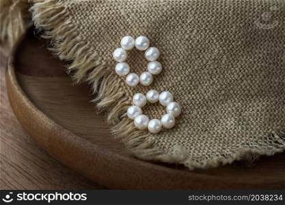 White pearl jewelry fashion photography. Earrings white pearl fashion photography. Earrings presented on Brown sackcloth. Women accessories. Focus and blur.