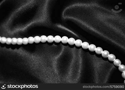 white pearl necklace on a dark black satin closeup