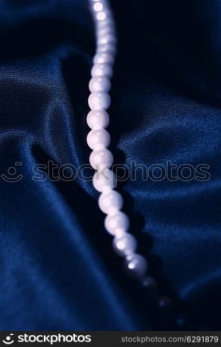 white pearl necklace on a dark blue silk close up