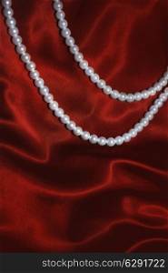 white pearl necklace on a red silk close up