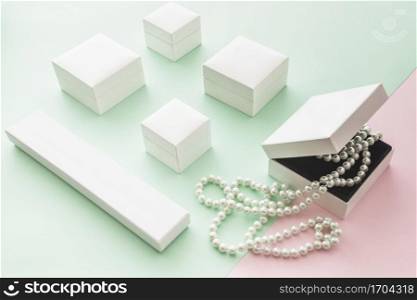 white pearls necklace with white boxes pink green pastel backdrop
