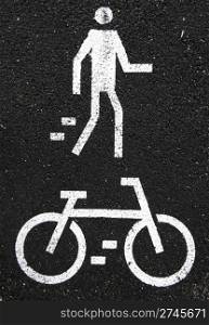white pedestrian and bicycle road signs painted on the asphalt surface