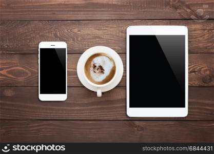 white phone tablet and coffee cup on wood table top view