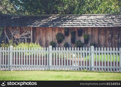 White picket fence in a garden with a woodshed