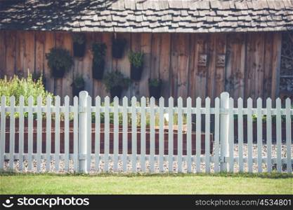 White picket fence in front af a wooden shed with plants