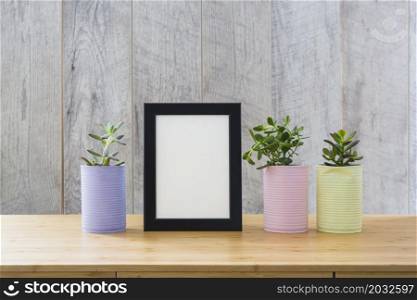 white picture frame with cactus plants painted can wooden desk