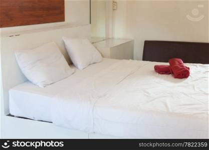 White pillows and bed linen. There are two pieces of red cloth on the bed. Koh Samet.
