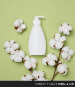White plastic bottle with pump on a green background. Containers for cosmetics	