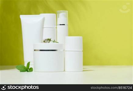 White plastic container tube, a jar with a lid for cosmetics on a green background with a shadow from a palm leaf. Advertising and promotion