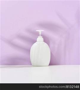 White plastic container with a pump for cosmetic liquid, liquid soap on the table