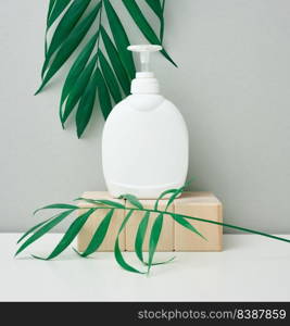 White plastic container with a pump for cosmetic liquid, liquid soap on the white table