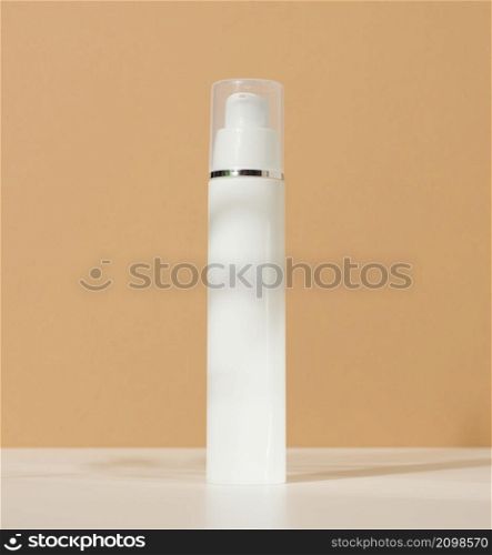 white plastic cosmetic bottle with dispenser and transparent cap on brown background. Packaging for cream, fluid and gel