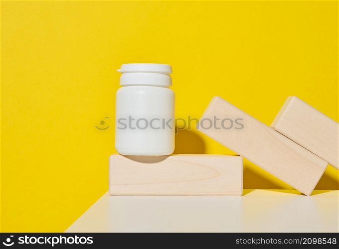 white plastic jar for pills, cream and medicines on a yellow background. Container for substances