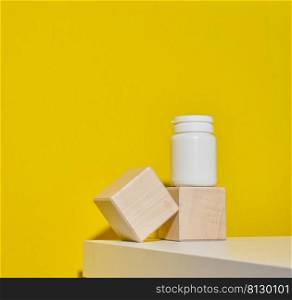 white plastic jar for pills, cream and medicines on a yellow background. Container for substances