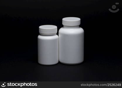 White plastic pill jars on a black background. Isolated. plastic pill jars