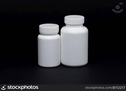 White plastic pill jars on a black background. Isolated. plastic pill jars