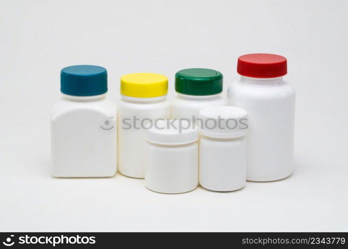 White plastic pill jars on a white background. Multi colored lids. Isolated. plastic pill jars