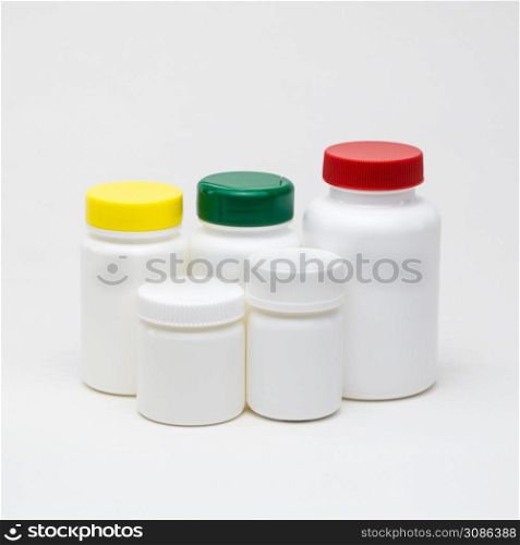 White plastic pill jars on a white background. Multi colored lids. Isolated. plastic pill jars