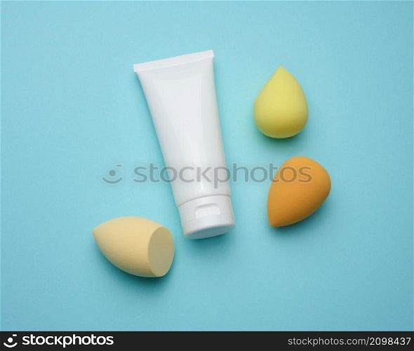 white plastic tube and oval new egg-shaped sponges for cosmetics and foundation, top view