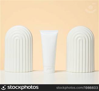 white plastic tube for cosmetic liquid products on a white table. Promotion and advertising of products, beige background