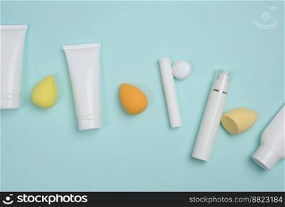 White plastic tubes for cream,≥l and other cosmetics and spon≥s on a blue background, top view
