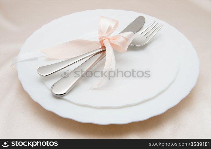 White plate, fork and knife on light background.