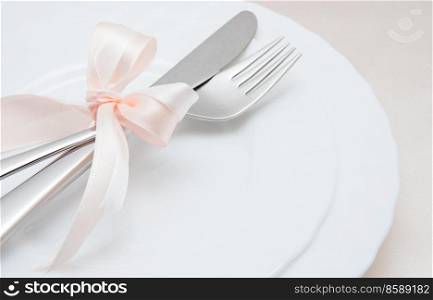 White plate, fork and knife on light background.